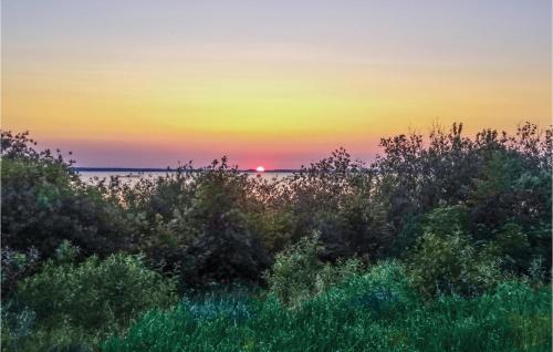 a sunset over the water with trees and grass at Nice Stacaravan In Retowo 4 in Gardna Wielka