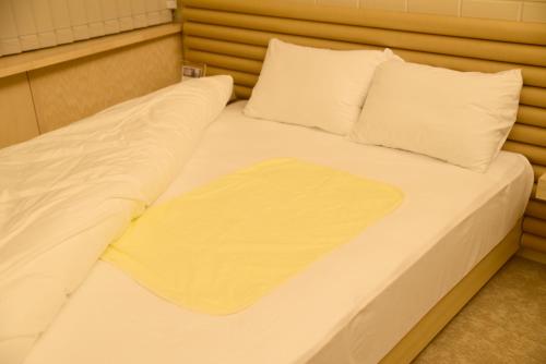 a bed with white sheets and pillows in a room at Shonai Hotel Suiden Terrasse in Tsuruoka