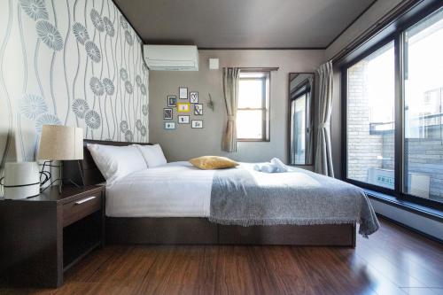 a bedroom with a bed and a large window at Calm Asakusa Kaminarimon Gate CLx in Tokyo