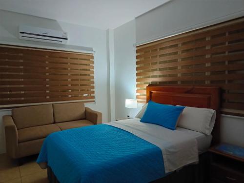 a bedroom with a blue bed and a chair at Teresita's House - Suites con cocina privada in Puerto Baquerizo Moreno