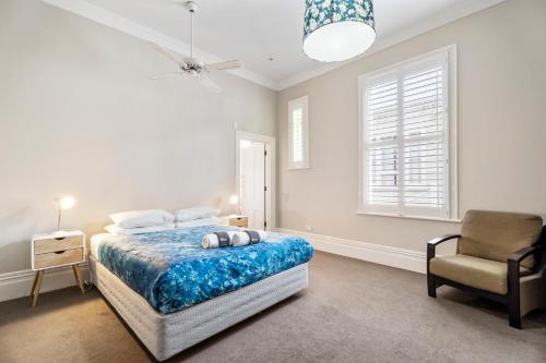 a white bedroom with a bed and a chair at Verandahs Parkside Lodge in Auckland