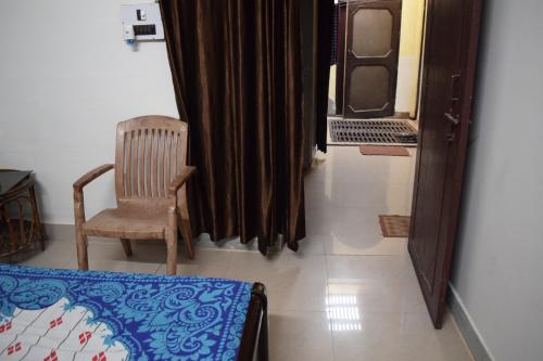 a room with a chair and a bed and a window at hive homestay in Mathura