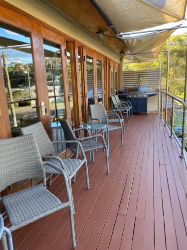 a porch with chairs and a table on a deck at Wanda House - Close to beach Linen Pets in Salamander Bay