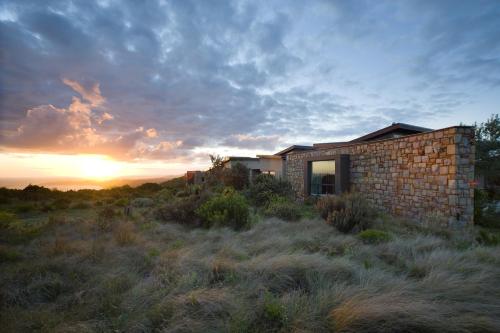 a house on a hill with the sunset in the background at Alkira Lodge in Brenton-on-Sea