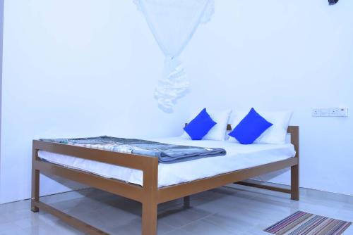 a bed with blue pillows on it in a room at Lake Forest Lodge in Udawalawe