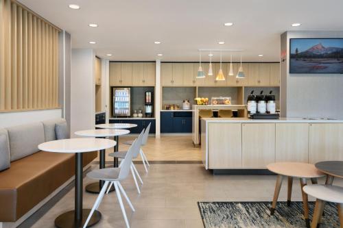 Un restaurante con mesas y sillas y una cocina. en TownePlace Suites by Marriott Oxford AL, en Oxford