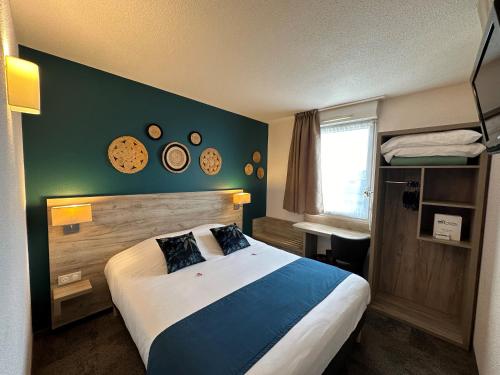 a bedroom with a large bed and a green wall at Brit Hotel Saumur in Distré