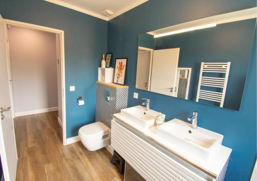 La salle de bains bleue est pourvue de 2 lavabos et de toilettes. dans l'établissement Maison 110m2, piscine, 3ch, à Callian