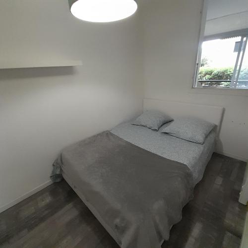 un lit dans une petite pièce avec une fenêtre dans l'établissement Joli T2 3mn mer. Proche commodité WiFi Parking, à La Seyne-sur-Mer
