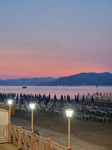 a beach with tables and chairs at sunset at Suite Hotel Nettuno in Sestri Levante