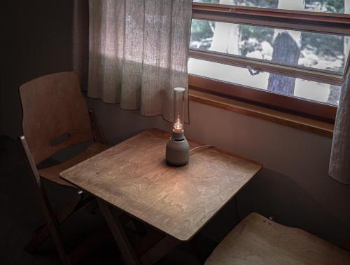 a lamp sitting on a table next to a window at Nold forest house 那須高原の森の中で心地よく暮らす宿 in Nasu