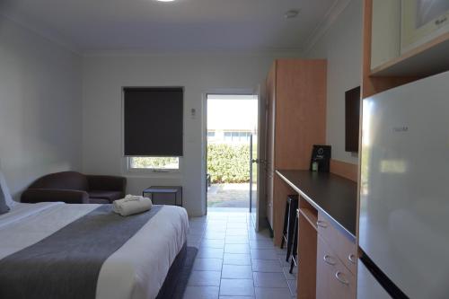 a hotel room with a bed and a kitchen and a couch at Tumut Apartments in Tumut