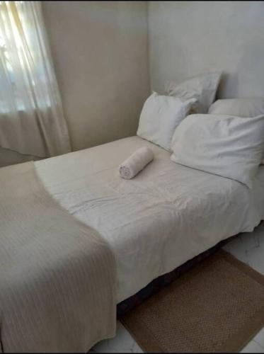 a white bed with a pillow on top of it at The Quaint Cottage in Livingstone