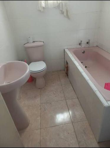 a bathroom with a toilet and a tub and a sink at The Quaint Cottage in Livingstone