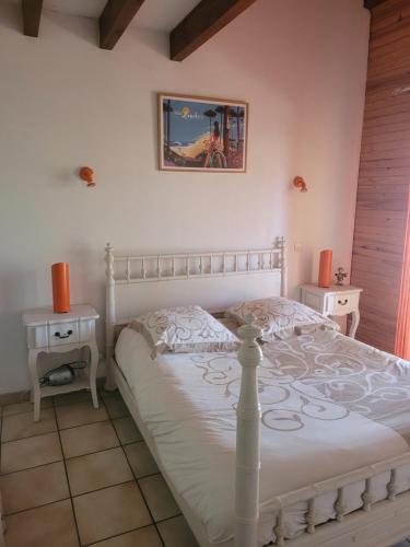 - une chambre avec un lit blanc et 2 tables de chevet dans l'établissement Maison avec piscine proche Contis plage (LANDES), à Saint-Julien-en-Born