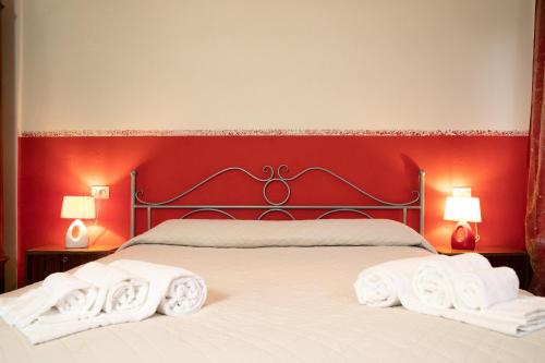 a bedroom with a red wall and a bed with towels at Agriturismo Valle Isola "La Tana del Gusto" in Comacchio