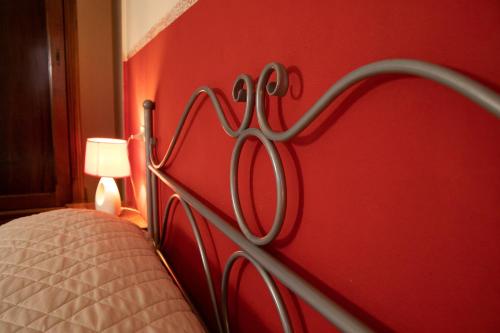 a bedroom with a red wall with a metal headboard at Agriturismo Valle Isola "La Tana del Gusto" in Comacchio
