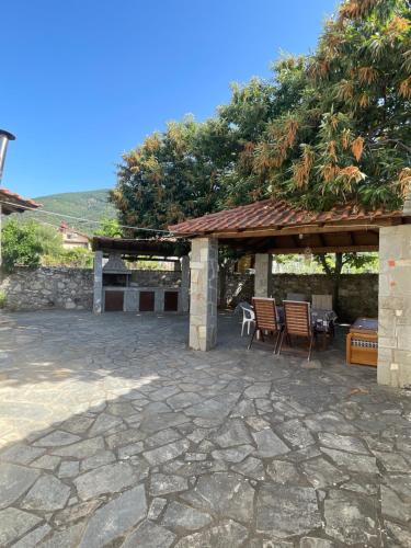 a stone patio with a pavilion with chairs and a table at Christina's Apartment in Stratónion