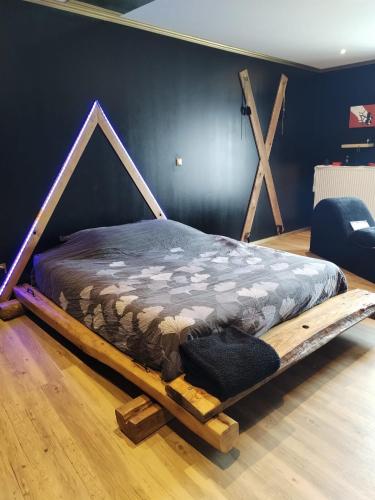 un lit avec un cadre en bois dans une chambre dans l'établissement Love-room l'eden du Désir, à Vecqueville