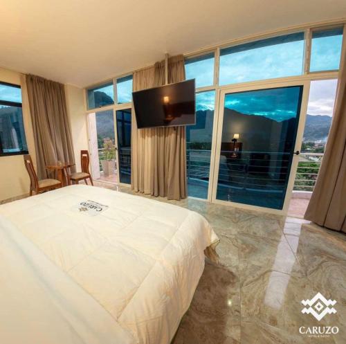 廷戈玛丽亚Caruzo Hotel and suites的一间卧室，配有一张大床和一台平板电视