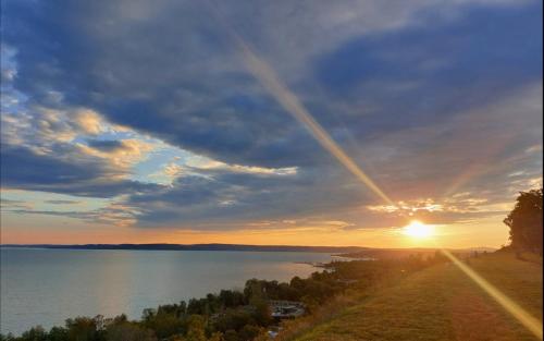 a sunset over a lake with the sun in the sky at Három Testvér Apartman in Siófok