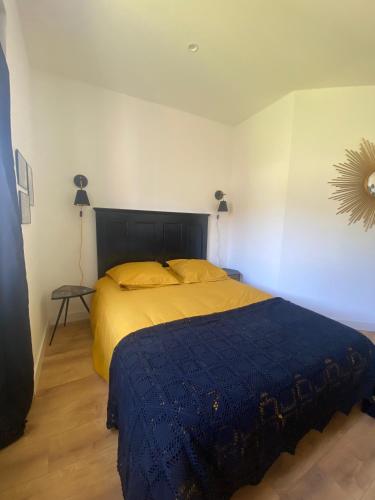 a bedroom with a bed with a blue blanket and a mirror at Chambre 2 dans Mas chez Sofi in Maubec