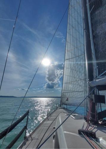 a sailboat on the ocean with the sun in the sky at Három Testvér Apartman in Siófok