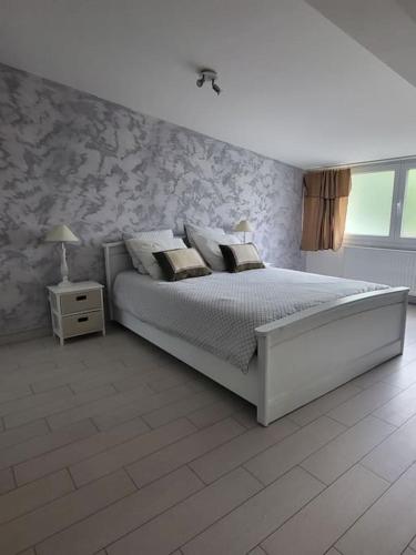 une chambre blanche avec un lit et une fenêtre dans l'établissement La campagne en ville, à Le Raincy