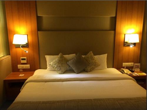 a bedroom with a large white bed with two lamps at Royal Orchid Central Vadodara in Vadodara
