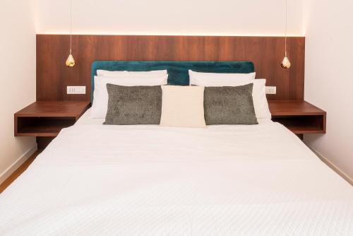 a large white bed with wooden headboard and pillows at Lifestyle Apartments Dante in Bardolino