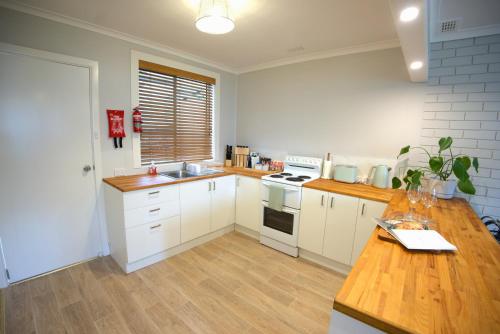 a kitchen with white cabinets and a wooden counter top at Ella's Beach Haven in Batehaven