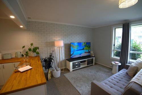 a living room with a couch and a flat screen tv at Ella's Beach Haven in Batehaven