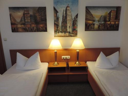 two beds in a hotel room with two lamps at Hotel Carl von Clausewitz in Burg bei Magdeburg