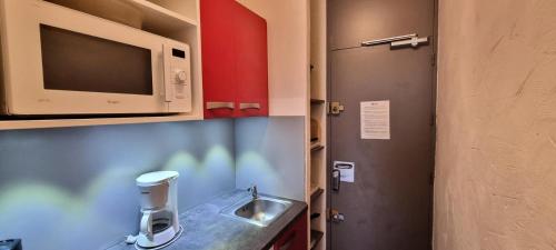 une petite cuisine avec un évier et un micro-ondes dans l'établissement Résidence Etoile - Studio pour 4 Personnes 954, à Aime La Plagne