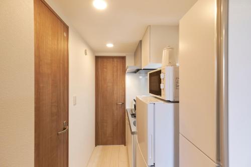a small kitchen with a refrigerator and a door at Sky Up Oshiage by Tranova in Tokyo