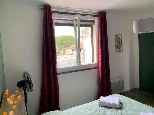 a bedroom with a window with red curtains at T2 Cosy - 70m2 au Coeur de ville in Graulhet