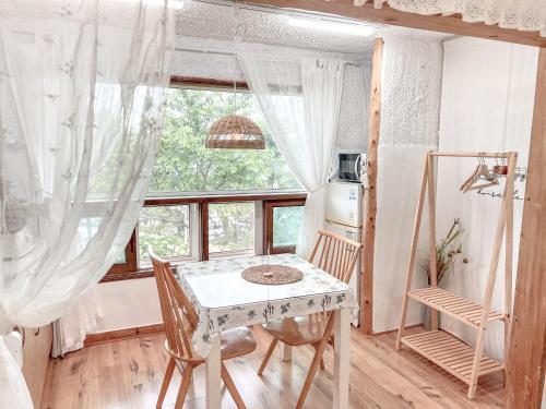 a table and chairs in a room with a window at Country House Exclamation Mark & Comma in Namhae