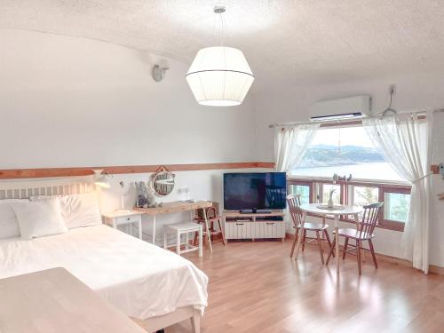 a bedroom with a bed and a table and a television at Country House Exclamation Mark & Comma in Namhae