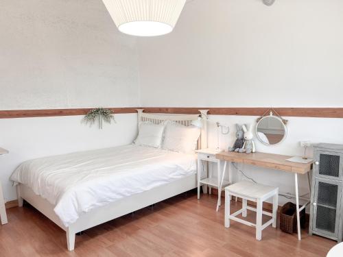 a bedroom with a white bed and a desk at Country House Exclamation Mark & Comma in Namhae