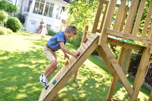a young boy playing on a wooden play structure at Hotel Schöngarten garni in Lindau