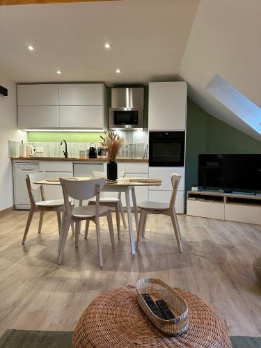 une cuisine avec une table et des chaises dans une pièce dans l'établissement Les Meublés de Luchon - L'échappée verte - Centre Luchon, Calme, Wifi, à Luchon
