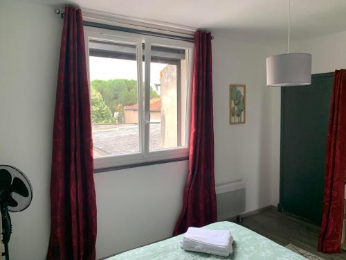 a bedroom with red curtains and a window at T2 Cosy - 70m2 au Coeur de ville in Graulhet