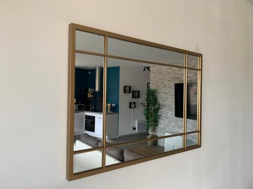 a mirror hanging on a wall on a wall at T2 Cosy - 70m2 au Coeur de ville in Graulhet