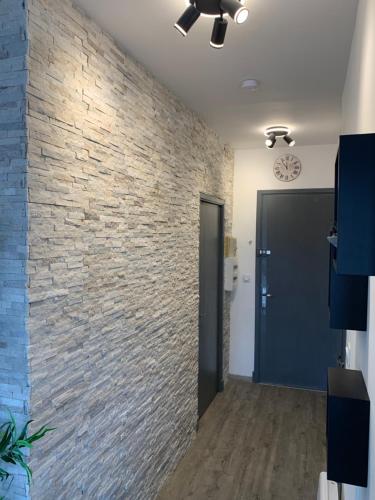 a lobby with a brick wall and a door at T2 Cosy - 70m2 au Coeur de ville in Graulhet