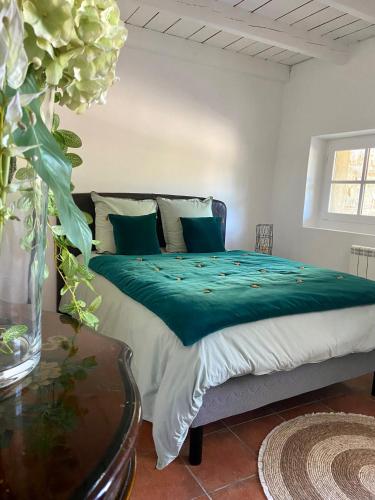 a bedroom with a bed with green sheets and a vase of flowers at La Serre Des Mourgues in Méjannes-lès-Alès