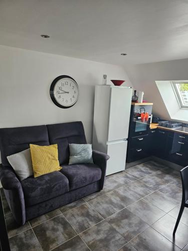 un salon avec un canapé et une horloge au mur dans l'établissement Appartement entre Terre et Mer, à Prat