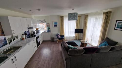 a living room with a couch and a kitchen at Number 15 Luxurious Two Bedroom Apartment in Exmouth