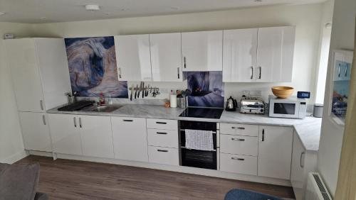 a kitchen with white cabinets and a sink and a microwave at Number 15 Luxurious Two Bedroom Apartment in Exmouth