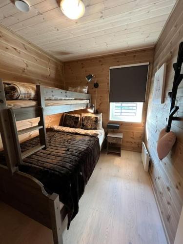 a log cabin bedroom with a large bed and a flat screen tv at ChaletMons, stor trivelig leilighet i Myrkdalen in Vossestrand
