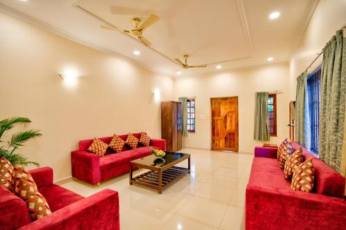 a living room with red couches and a table at Portu Stay Goa in Vagator